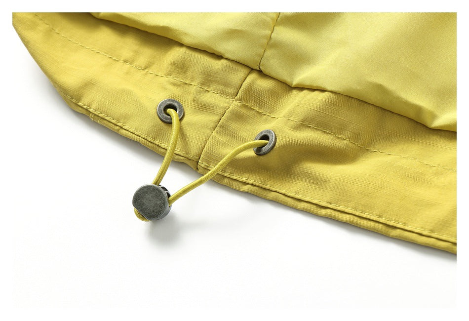Close-up of the mustard-yellow jacket's hem drawcord threaded through metal eyelets.