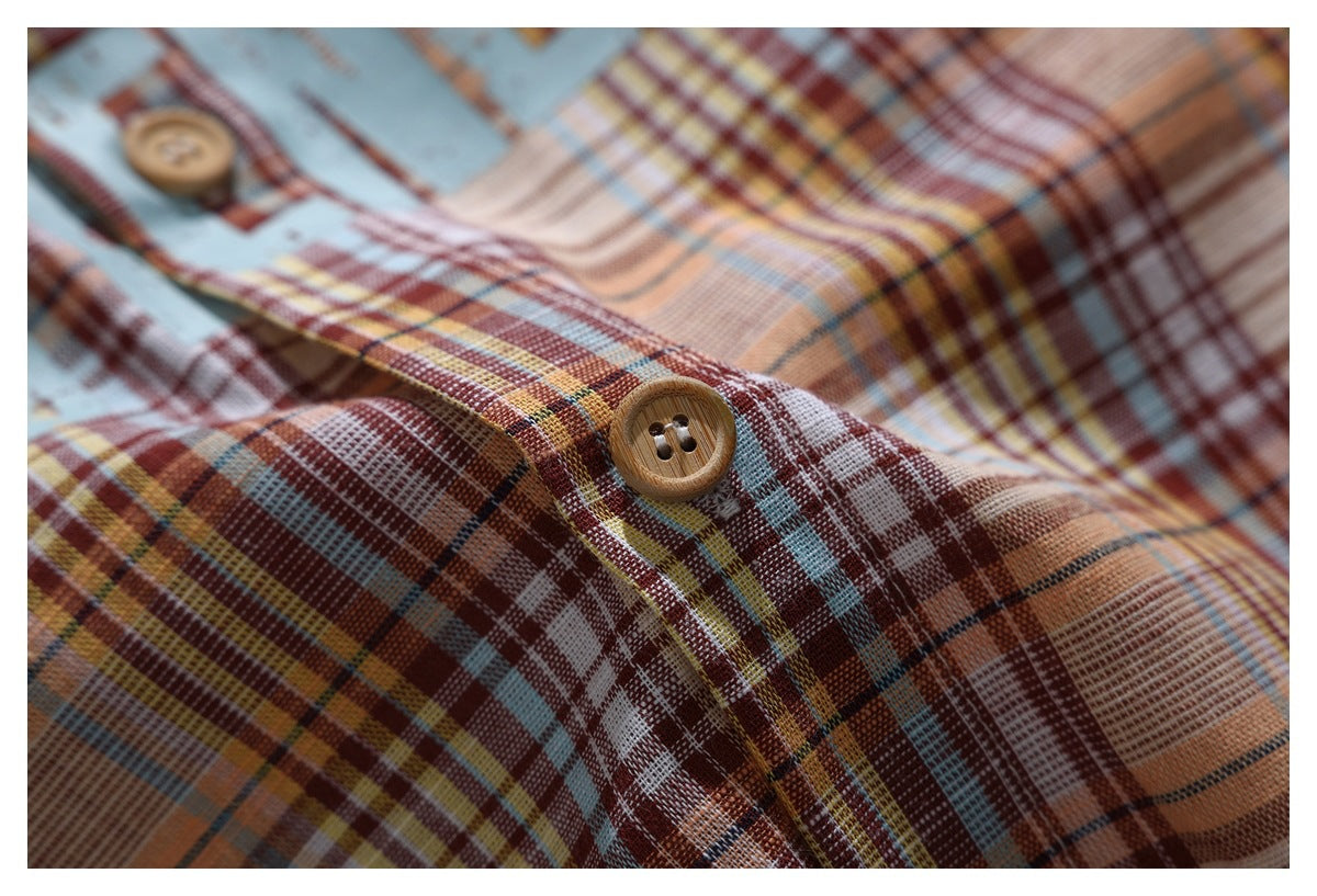 Macro view of a tan button on the shirt's multicolor plaid fabric.