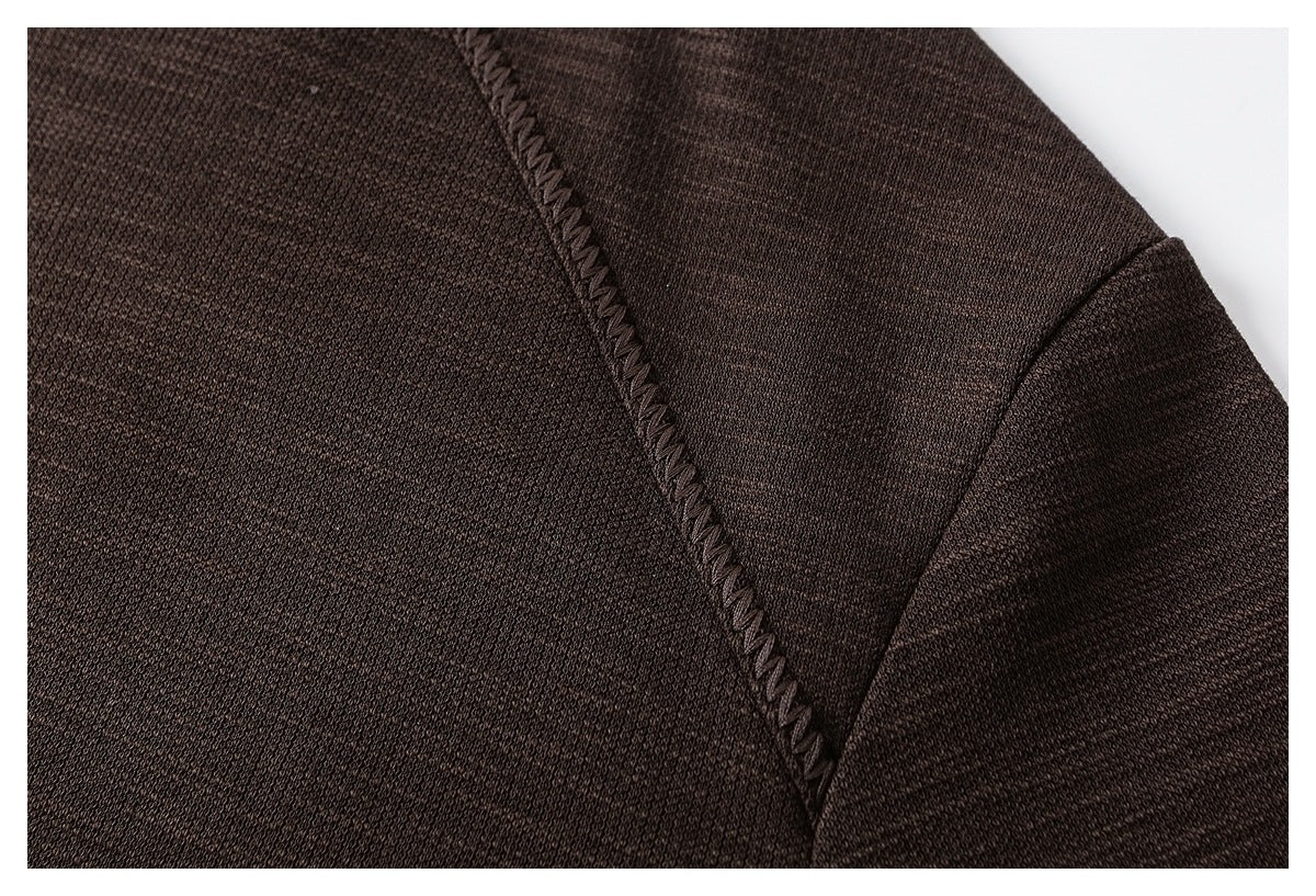 Close-up of a dark brown sweatshirt's raglan seam and textured knit fabric.