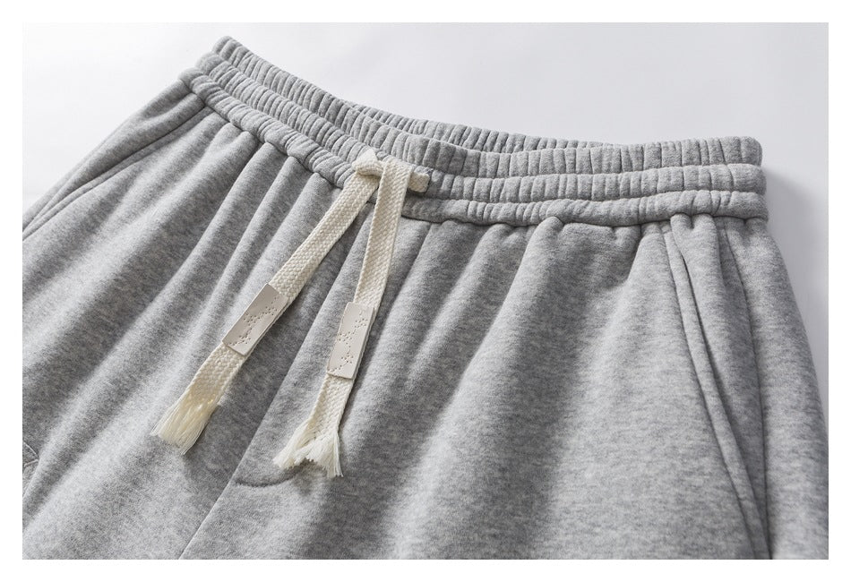 Close-up of gray sweatpants showing the elastic waistband and cream drawstrings.