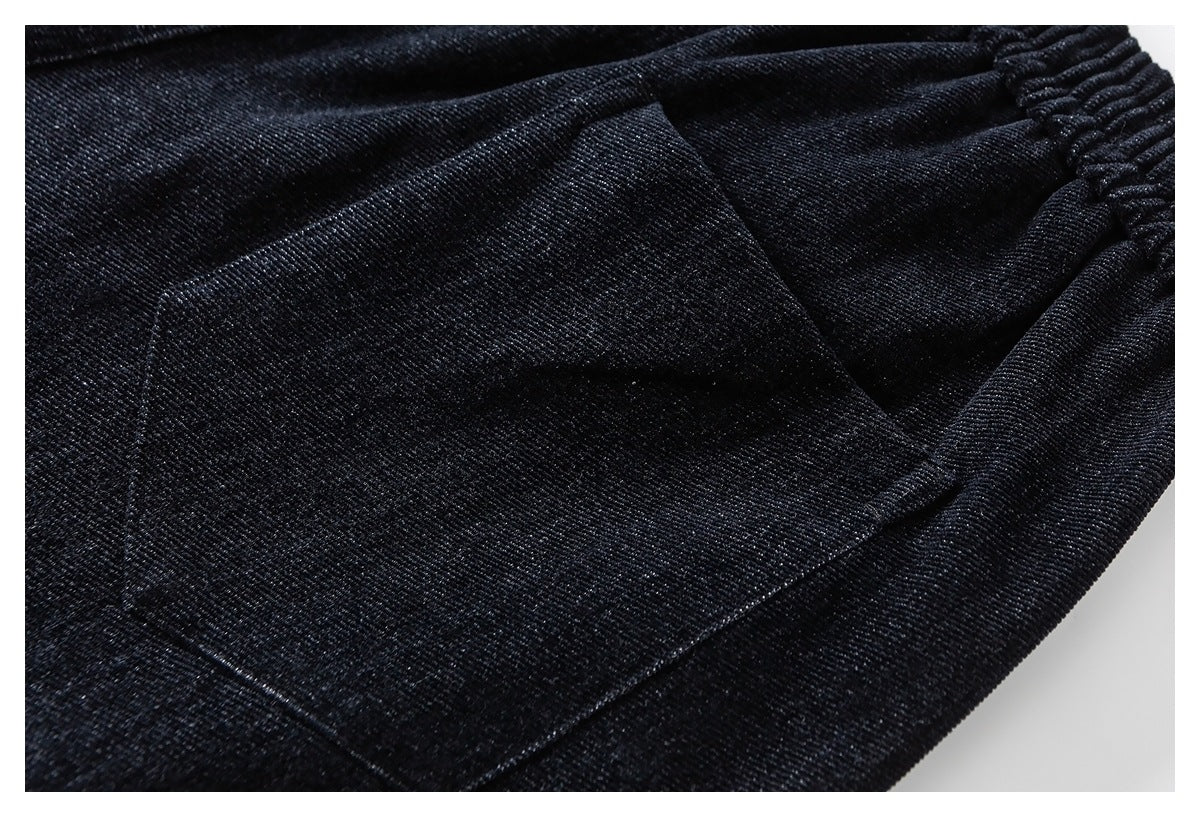 Close-up of black pants showing a large patch pocket and gathered elastic waistband.