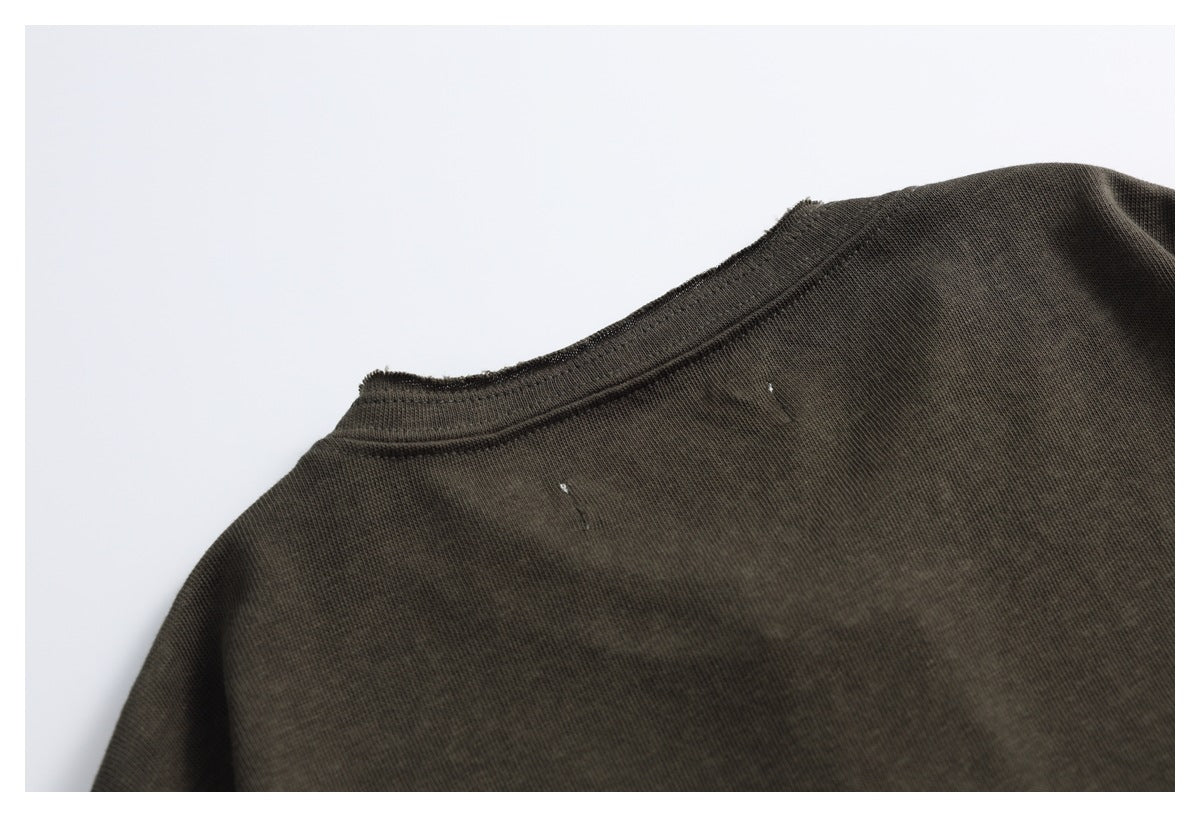 Close-up of a dark charcoal-brown garment neckline and shoulder seam against a light background.