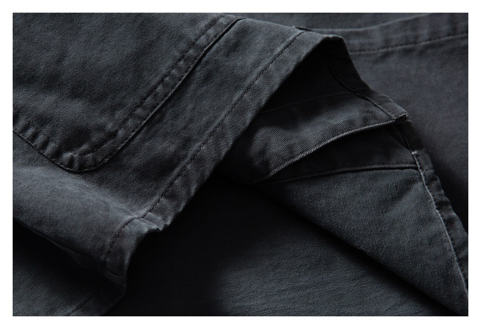 Close-up of overlapping panels and stitched seams on a dark charcoal garment.