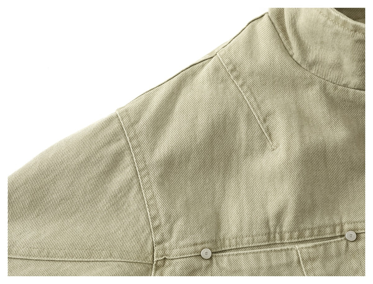Close-up of the light khaki jacket's shoulder seams and chest seam with small metal buttons.