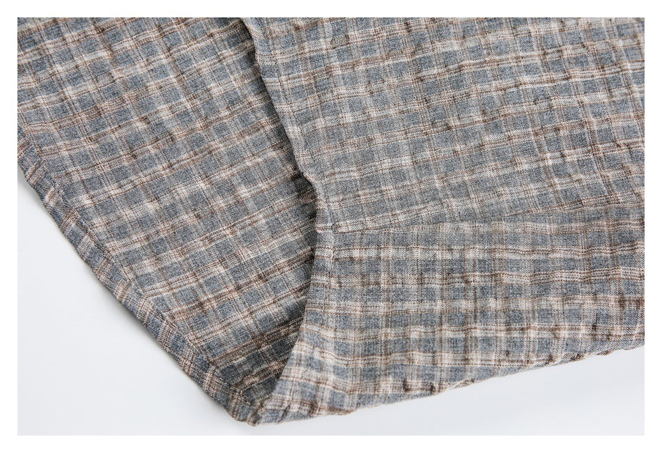 Close-up of the plaid shirt's folded lower edge and stitched hem.