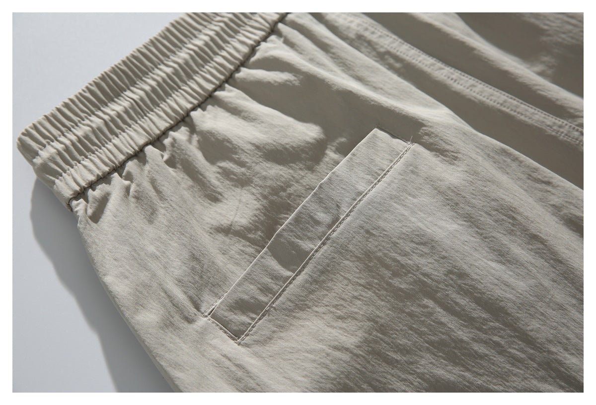 Close-up of light beige pants showing an elastic waistband and a stitched pocket.