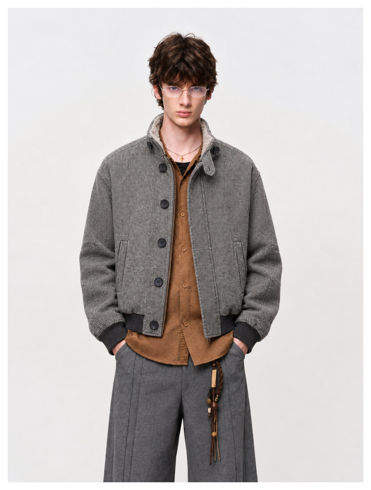 Front view of a model wearing a gray patterned bomber jacket over a brown shirt, with ribbed trim and a fleece-lined collar.