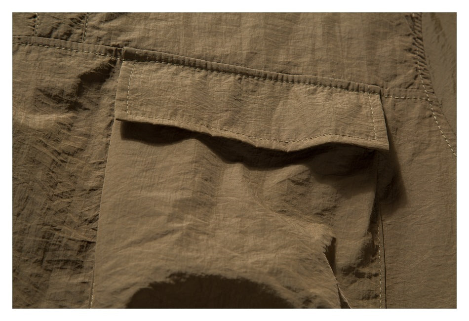 Close-up of a brown garment’s large flap pocket and visible stitching.