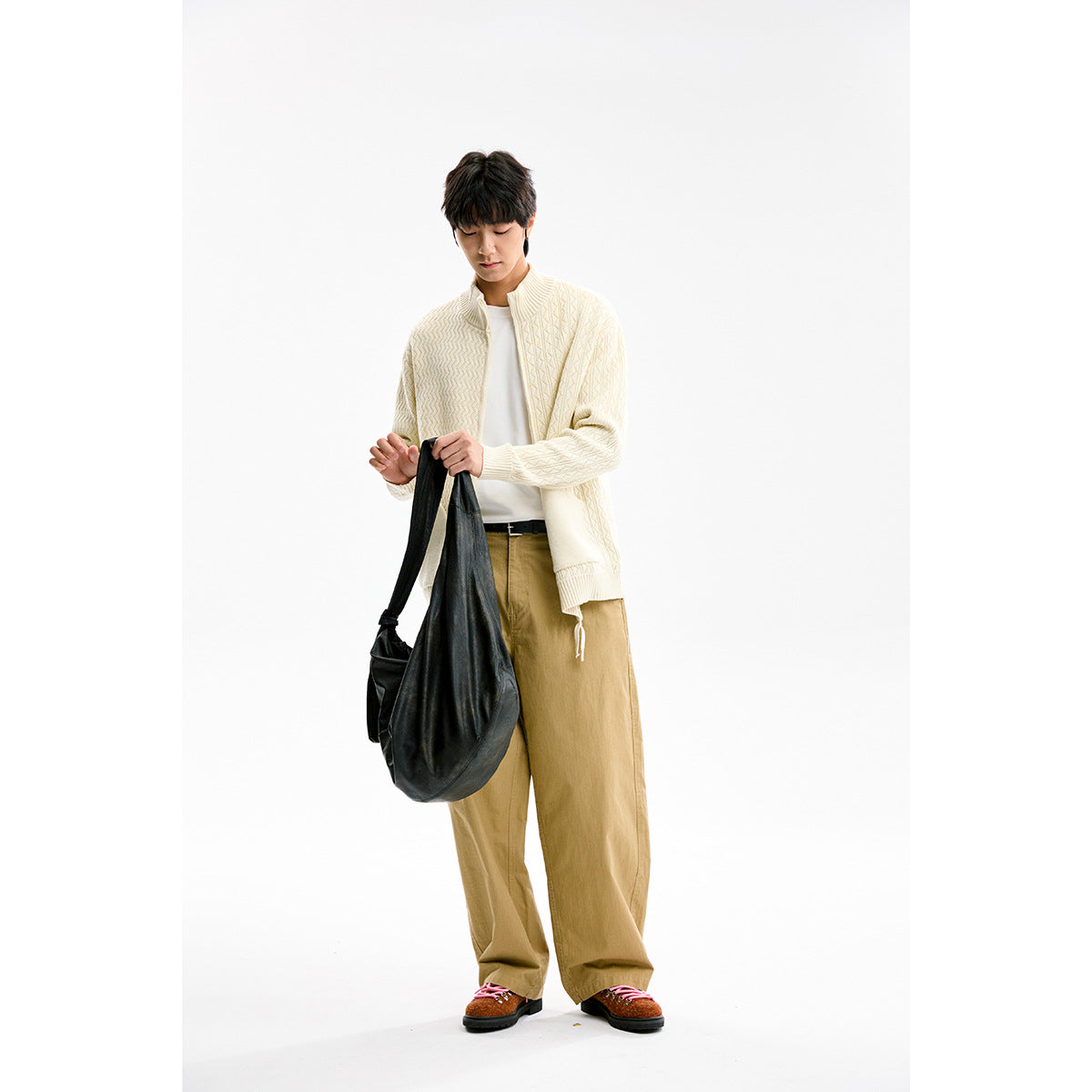 Model wearing an ivory textured knit zip cardigan with a ribbed stand collar and tan trousers.