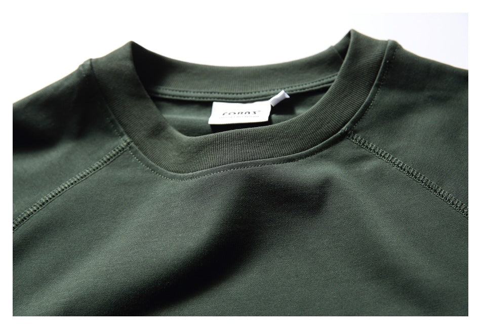 Close-up of the dark green T-shirt's crew neckline, raglan seams, and sewn neck label.