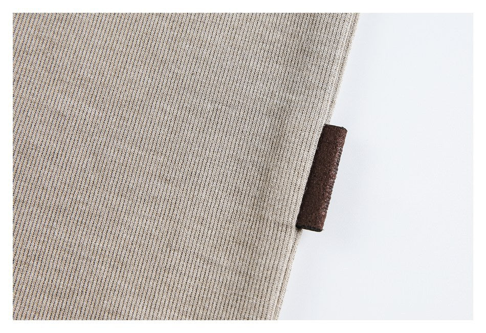 Close-up of taupe knit fabric with a small blank dark brown fabric tab at the edge.