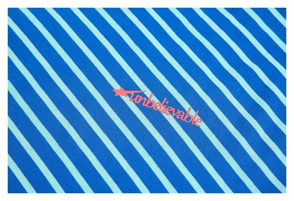 Close-up of blue and pale aqua diagonal stripes with pink “Unbelievable” lettering.