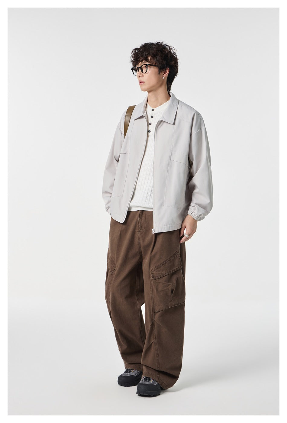 Full-length view of a model wearing a light gray zip-front jacket with brown cargo trousers.