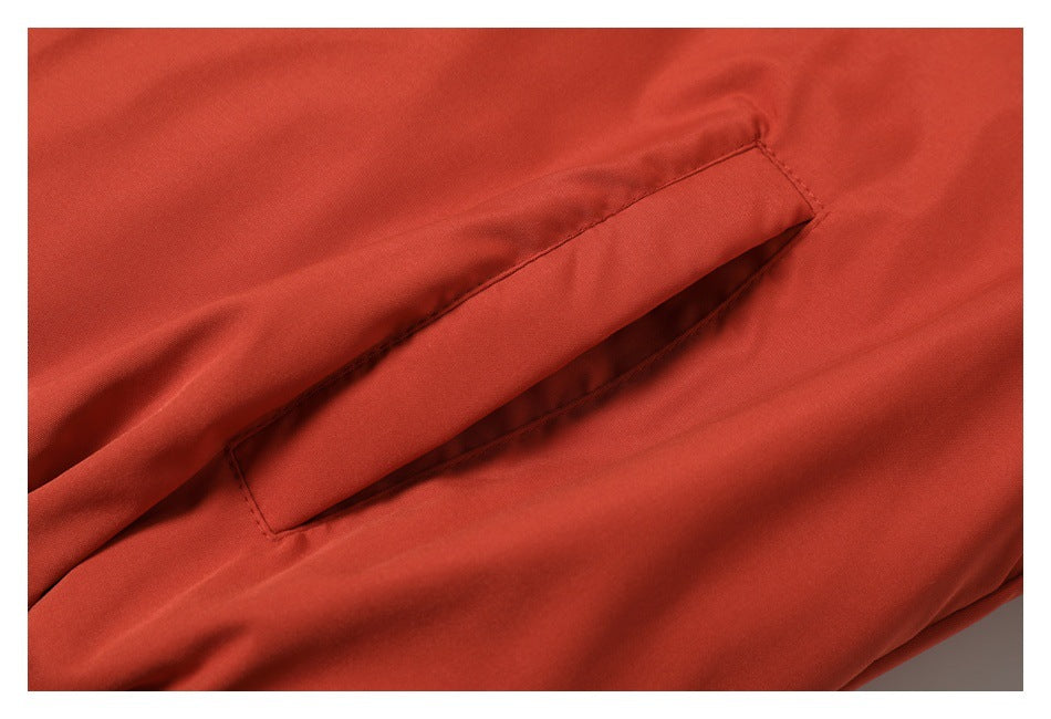 Close-up of a slanted welt pocket on rust-red coat fabric.