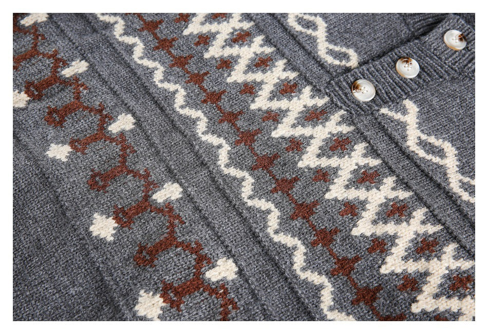 Close-up of a charcoal knit sweater’s cream and rust geometric bands and three-button placket.