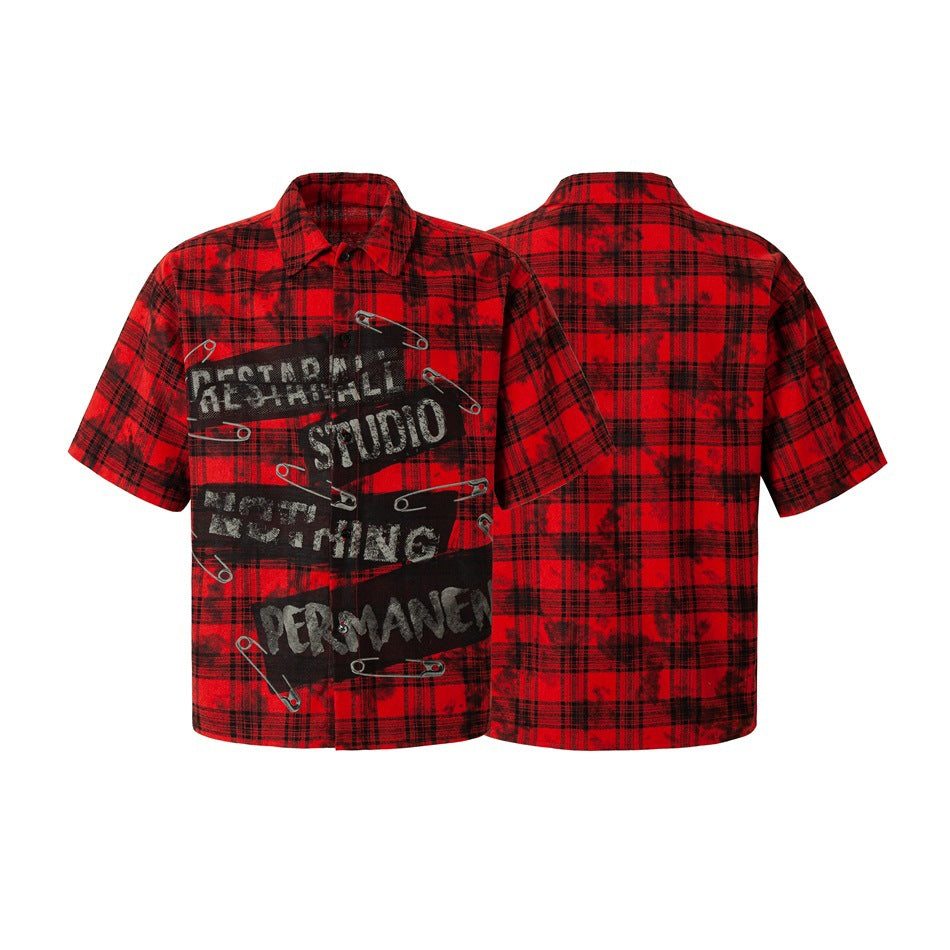 Front and back views of a red-and-black plaid short-sleeve shirt; the front has a distressed graphic with safety-pin artwork.