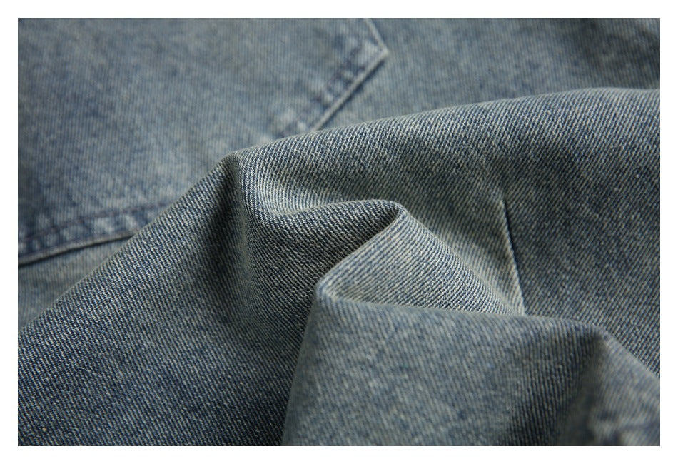 Macro close-up of the woven texture and folds of gray-blue denim fabric.