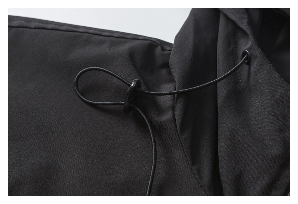 Close-up of a black jacket's adjustable hood drawcord and cord lock.