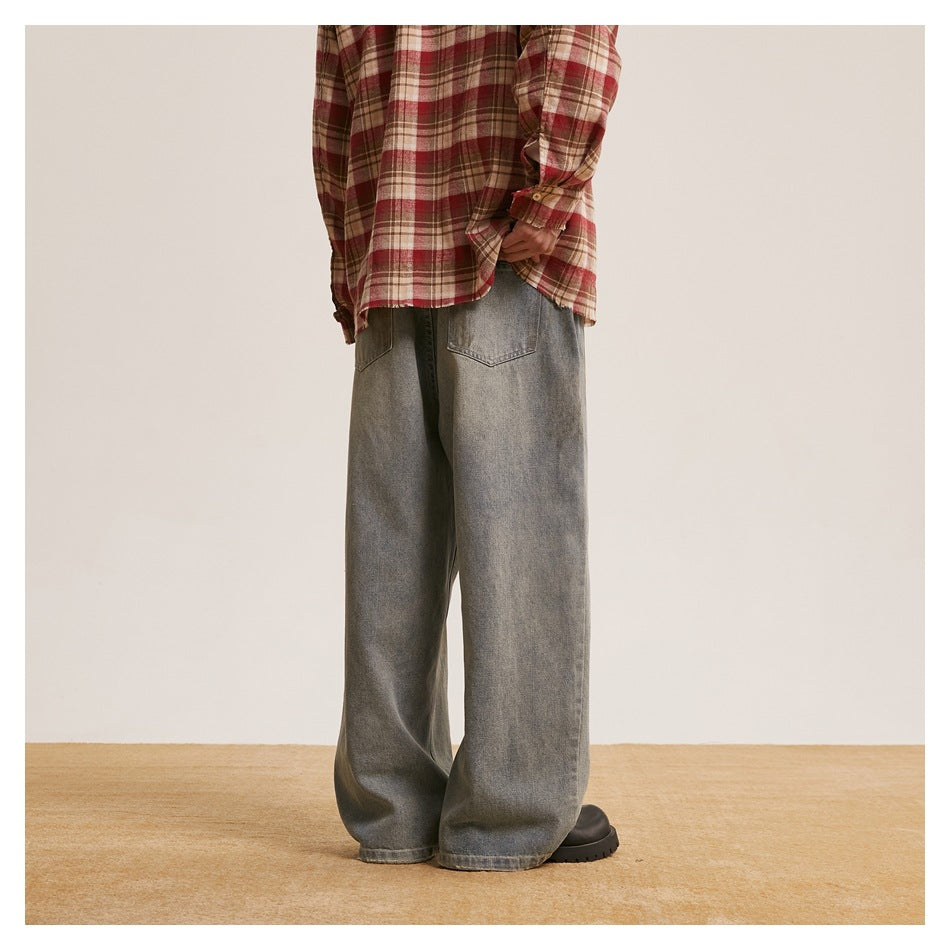 Back view of a model wearing loose gray washed jeans with two patch pockets.
