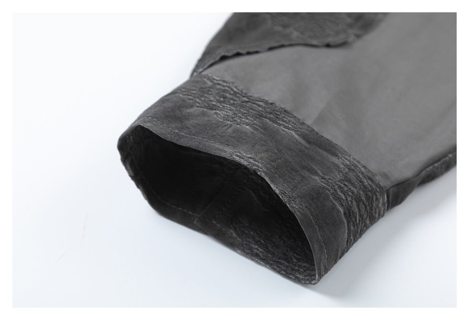 Close-up of a charcoal garment opening with a dark, textured folded edge.