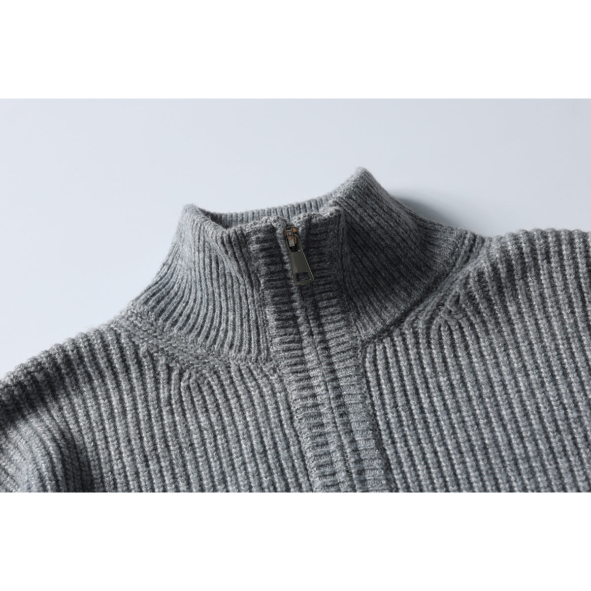 Close-up of a gray rib-knit zip sweater showing its high collar, shoulder seams and zipper.
