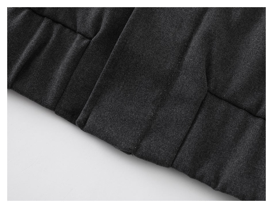 Close-up of charcoal coat panel seams and folded fabric along the edge.
