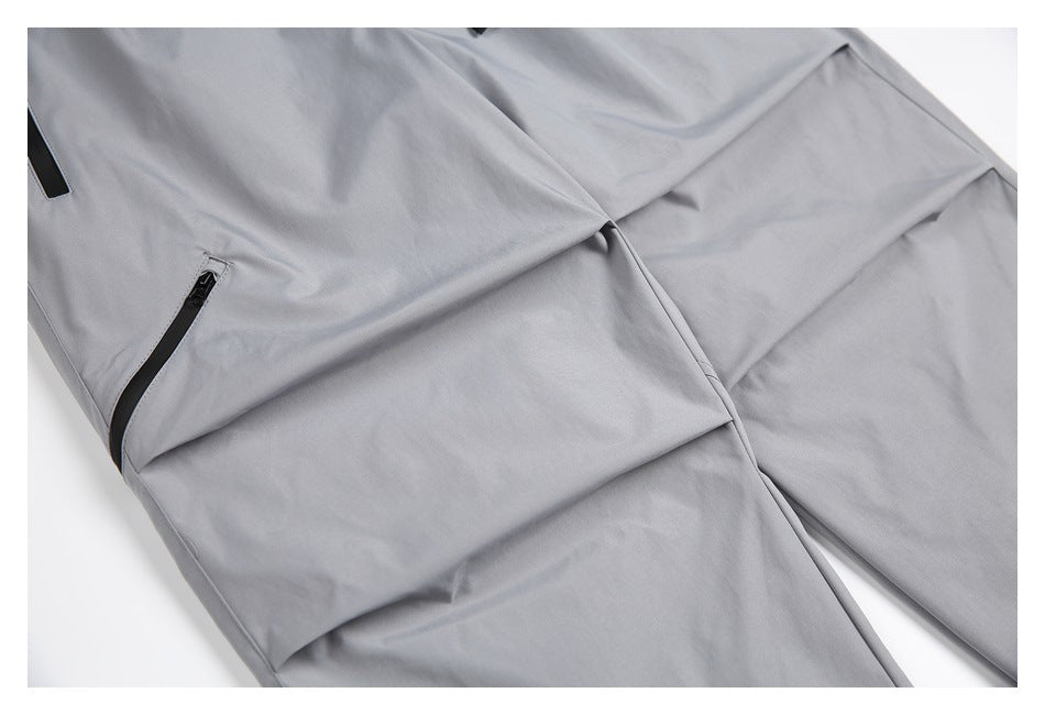 Close-up of the light gray pants' leg panels, seams, and a black zip pocket.