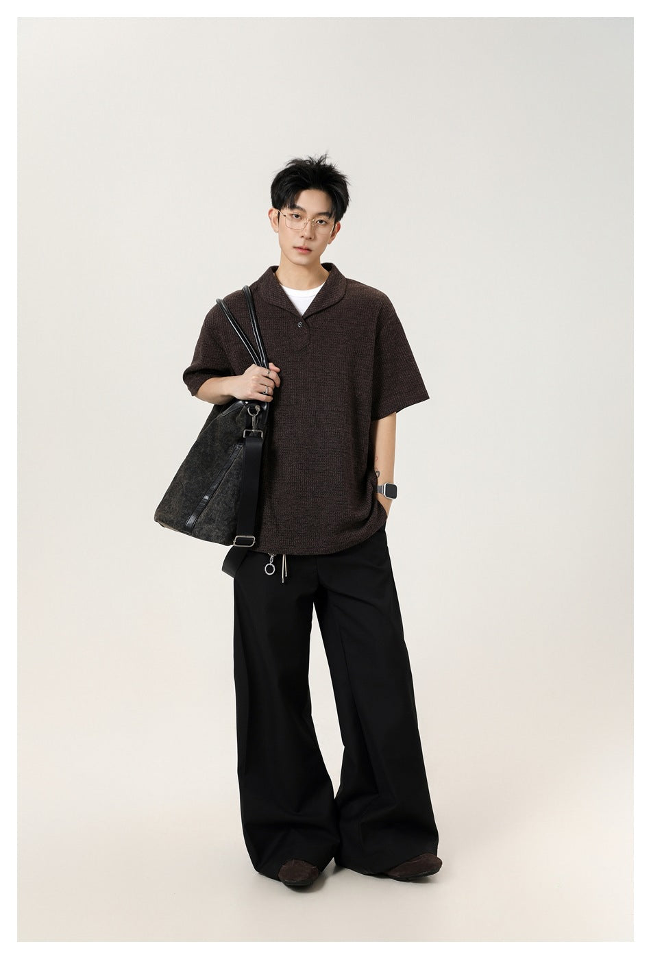 Full-length model wearing a dark brown short-sleeve knit polo shirt with wide-leg black trousers.
