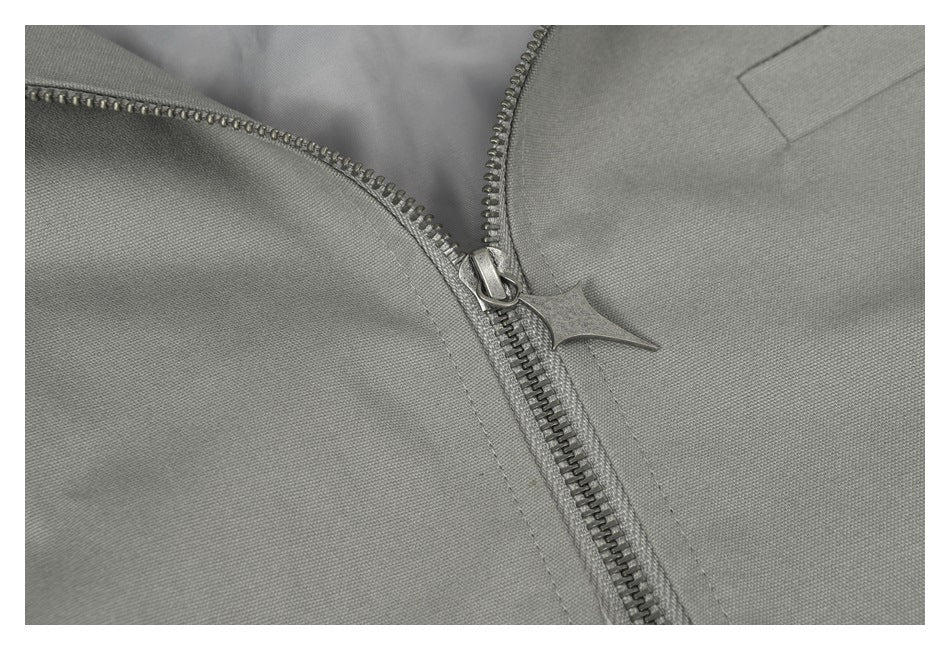 Close-up of the gray jacket's metal zipper, distinctive pull and surrounding fabric.