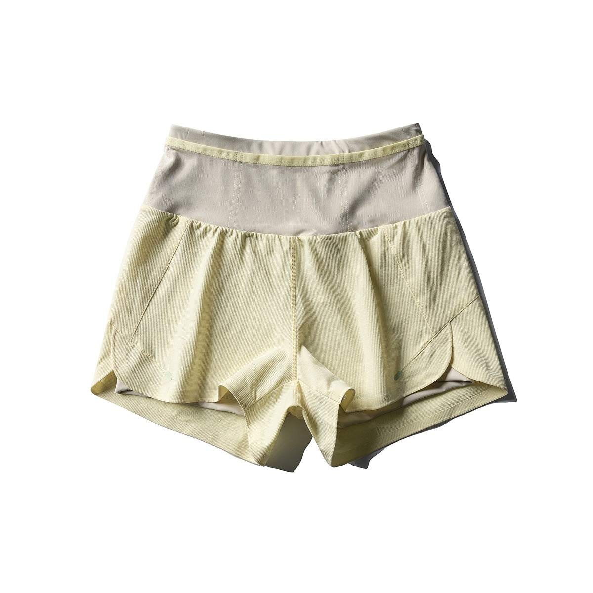 Pale yellow double-layer athletic shorts, flat lay front view with taupe waist panel and scalloped hems