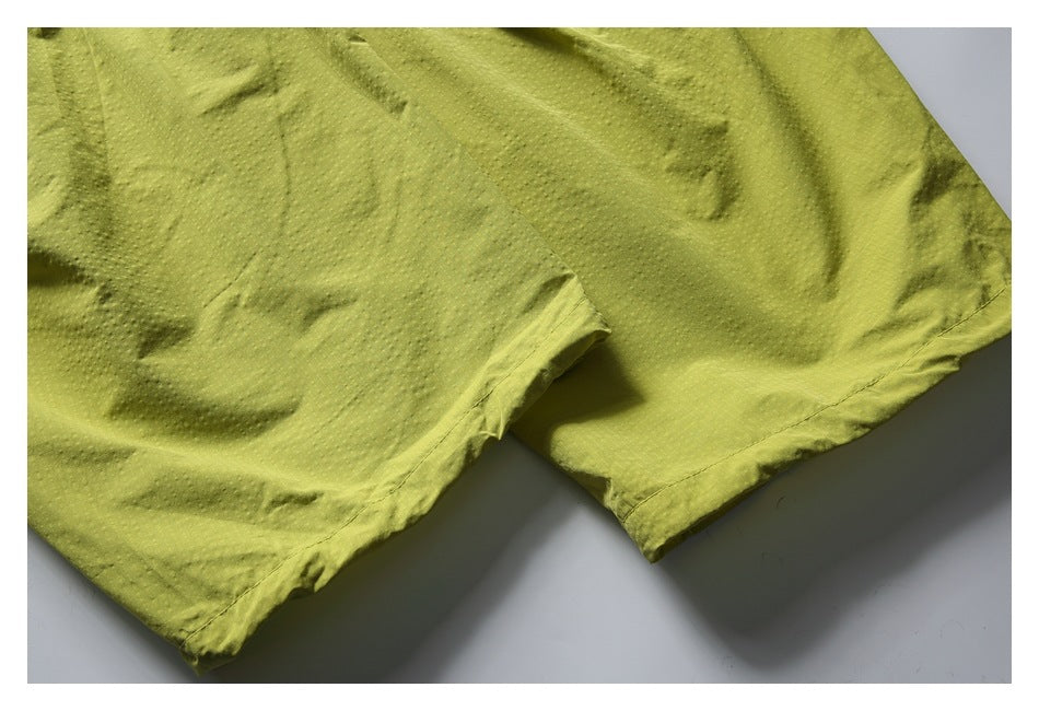 Close-up of the lime-yellow shorts' leg openings and stitched hems.