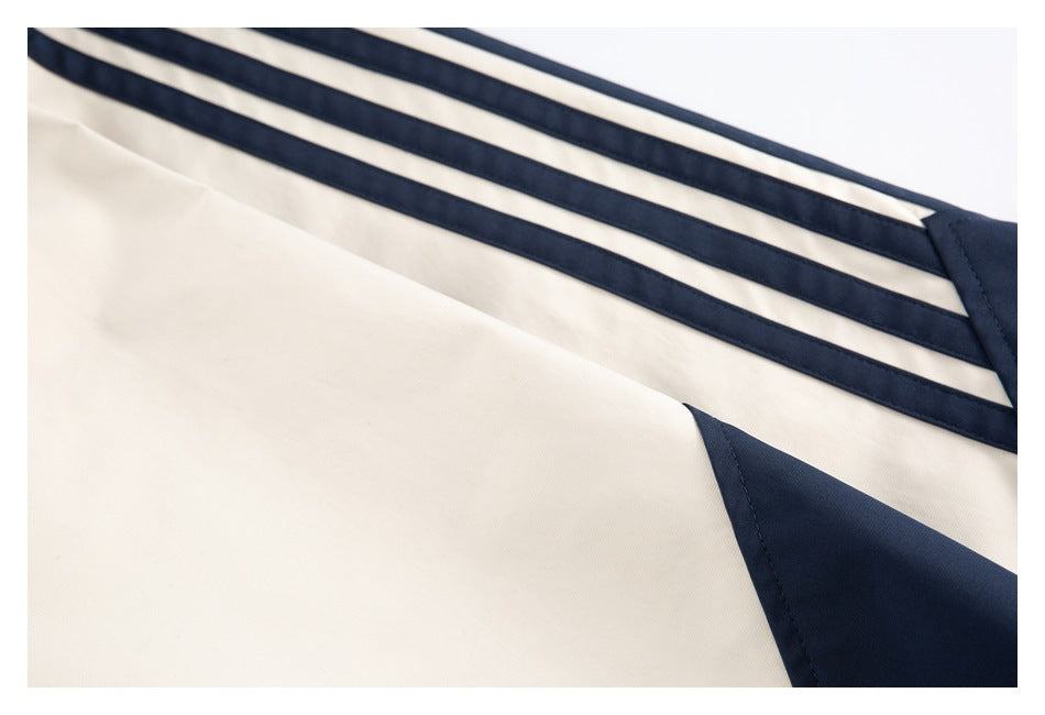 Close-up of cream jacket fabric with three parallel navy stripes and a navy panel.