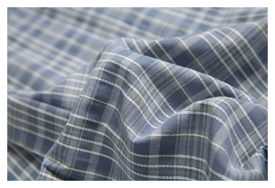 Close-up of blue-gray plaid fabric gathered into soft folds, showing its woven pattern.