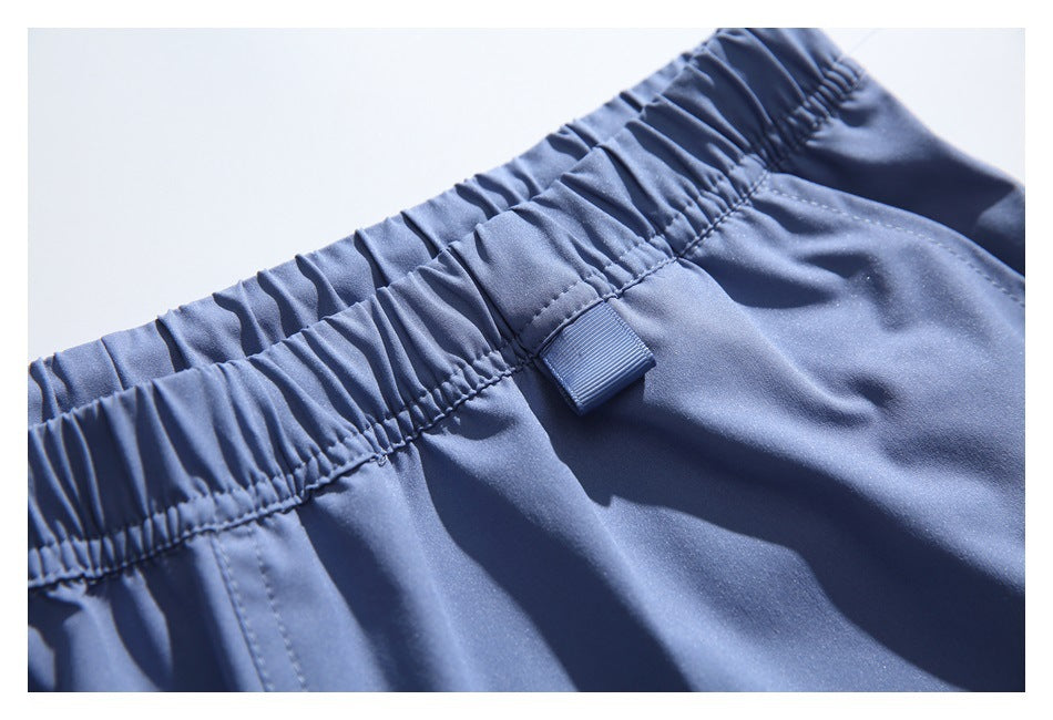 Close-up of the gathered elastic waistband and small fabric loop on blue shorts.