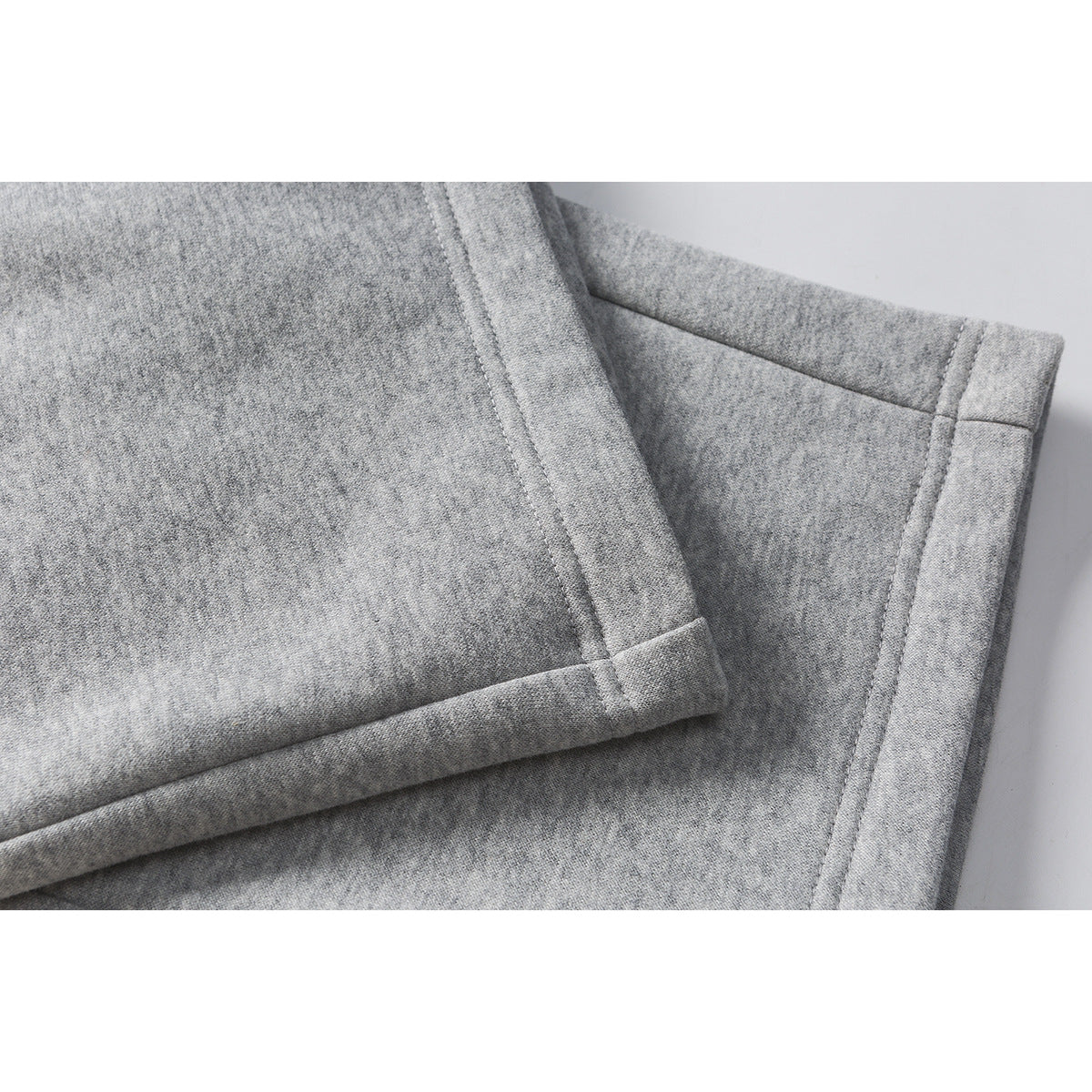 Close-up of gray sweatpants showing a stitched, folded leg hem.