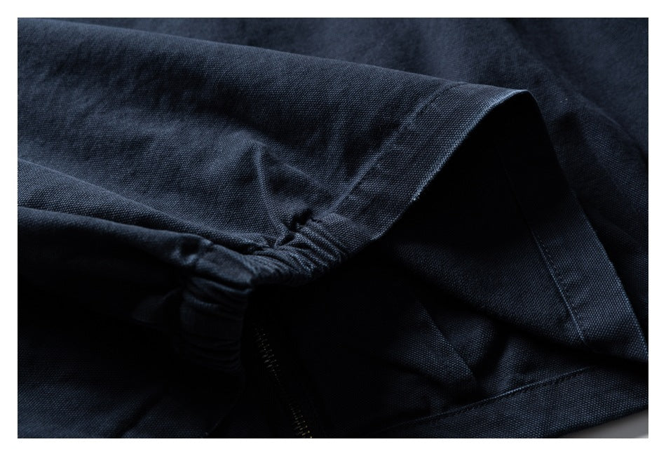 Close-up of gathered stitching, a seam, and zipper on a dark navy garment.