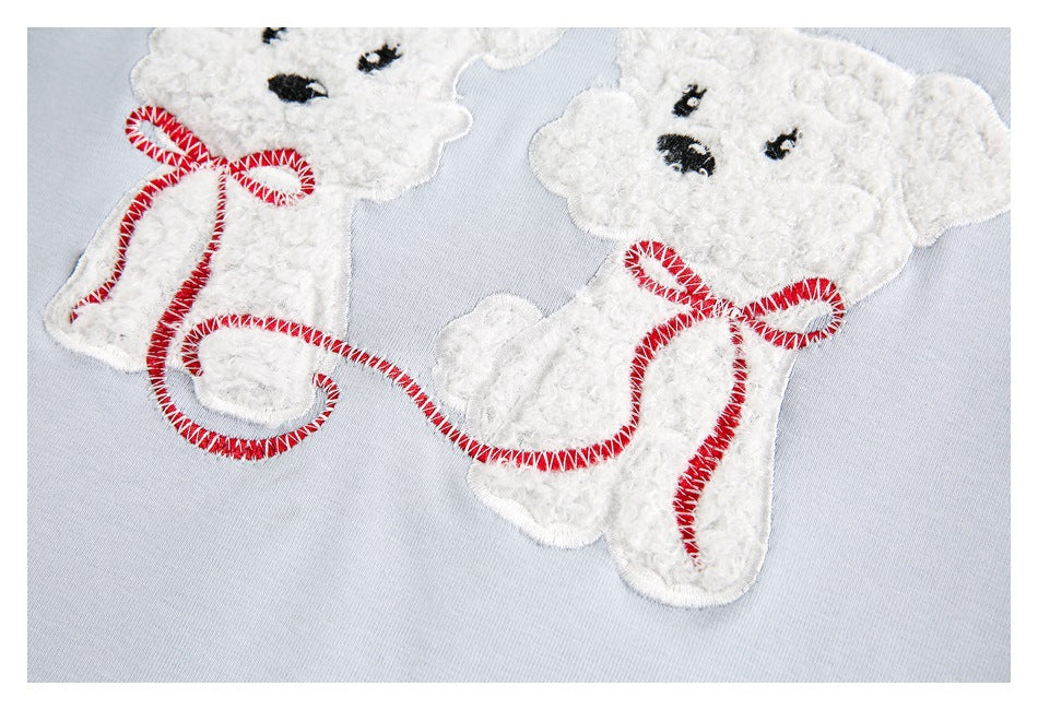 Close-up showing the textured white teddy bear appliqué and red stitching on pale blue fabric.