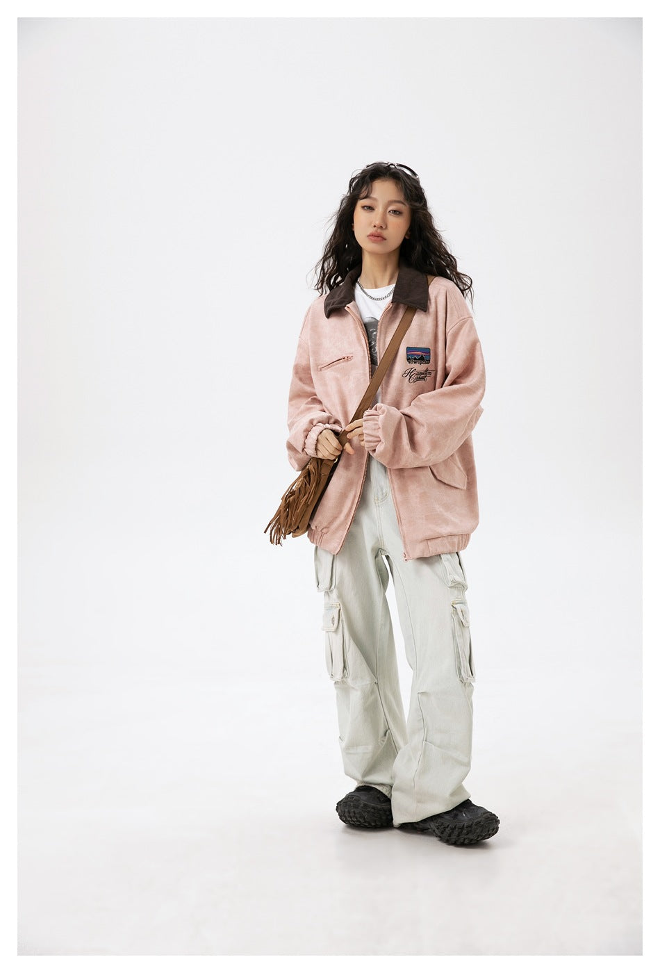 Full-length view of a model wearing a dusty pink jacket with dark collar and pale cargo pants.