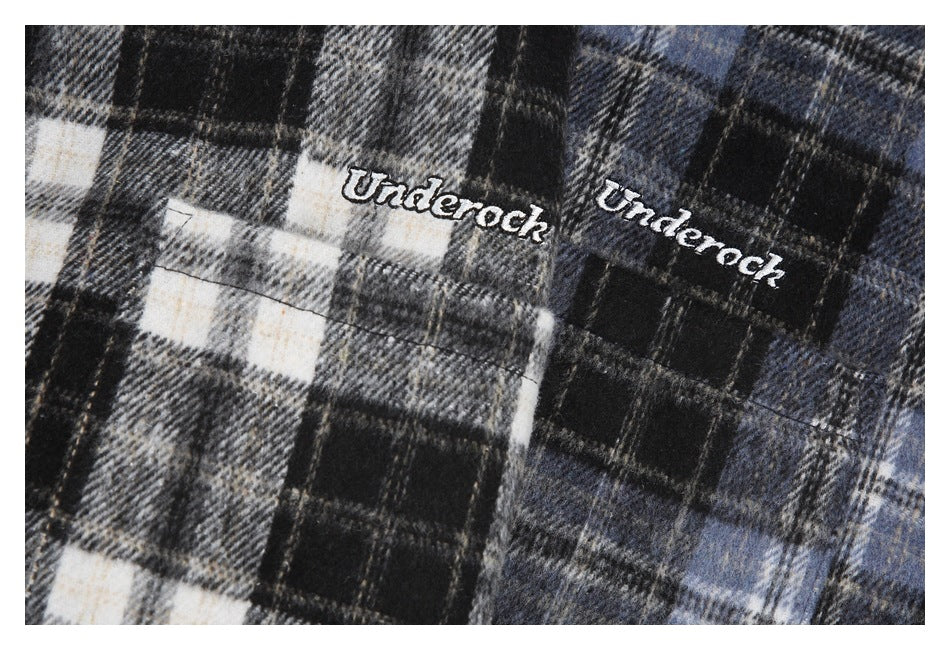 Close-up of embroidered script lettering on black, gray, cream, and blue plaid fabric.