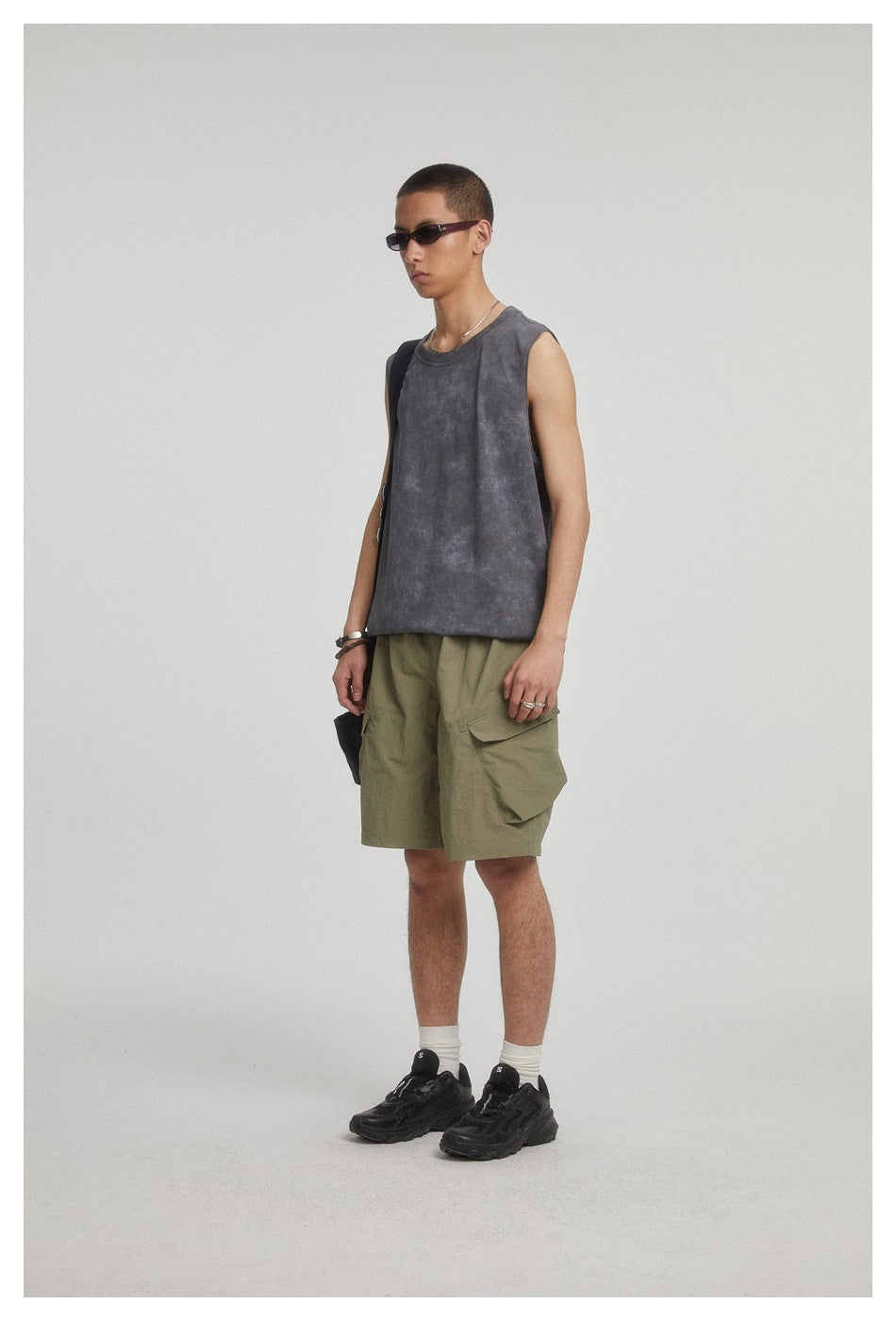 Model wearing a charcoal sleeveless top and olive cargo shorts, shown at an angle.