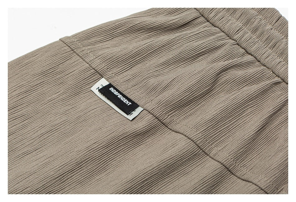 Close-up of taupe ribbed pants with a black Independent label.