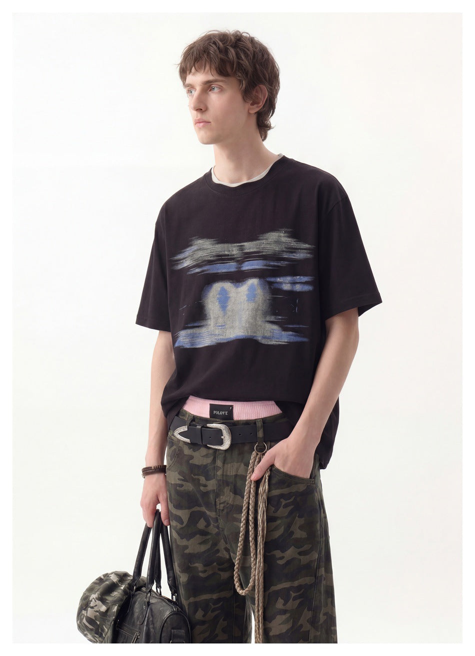 Closer view of a model wearing a black T-shirt with a blue and gray abstract chest graphic.