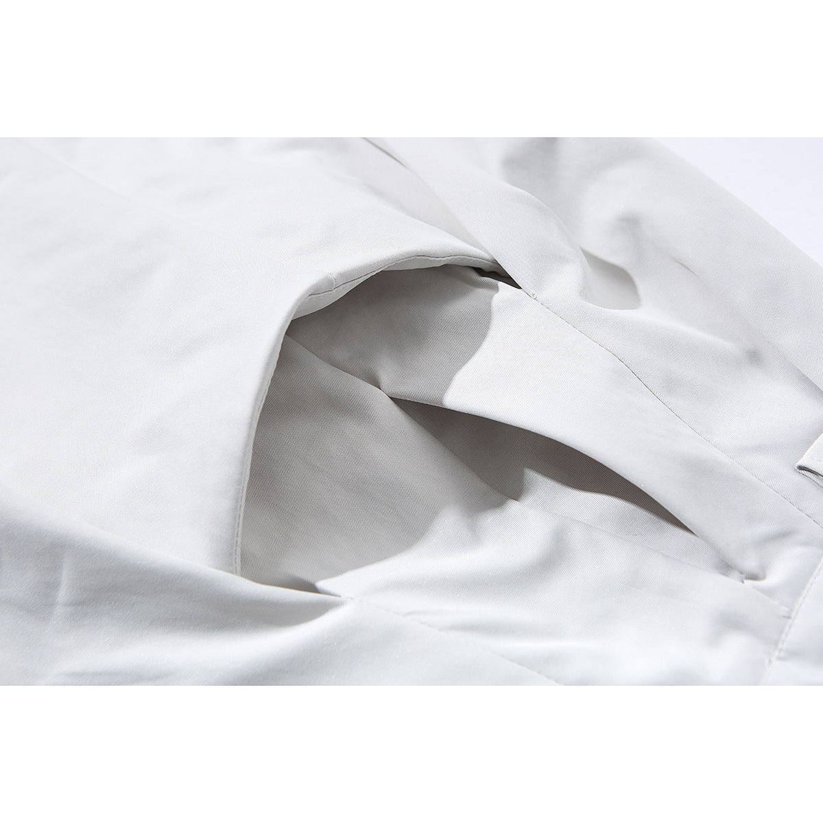 Close-up of the white shorts' angled side pocket opening and stitching.