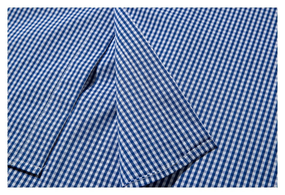 Close-up of blue-and-white gingham shirt fabric with overlapping folded edges and a stitched hem.
