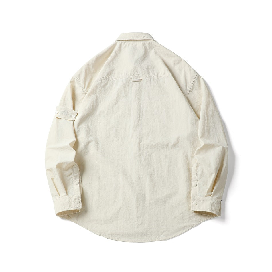Back view of an ivory long-sleeve shirt laid flat, showing a curved hem and buttoned cuffs.