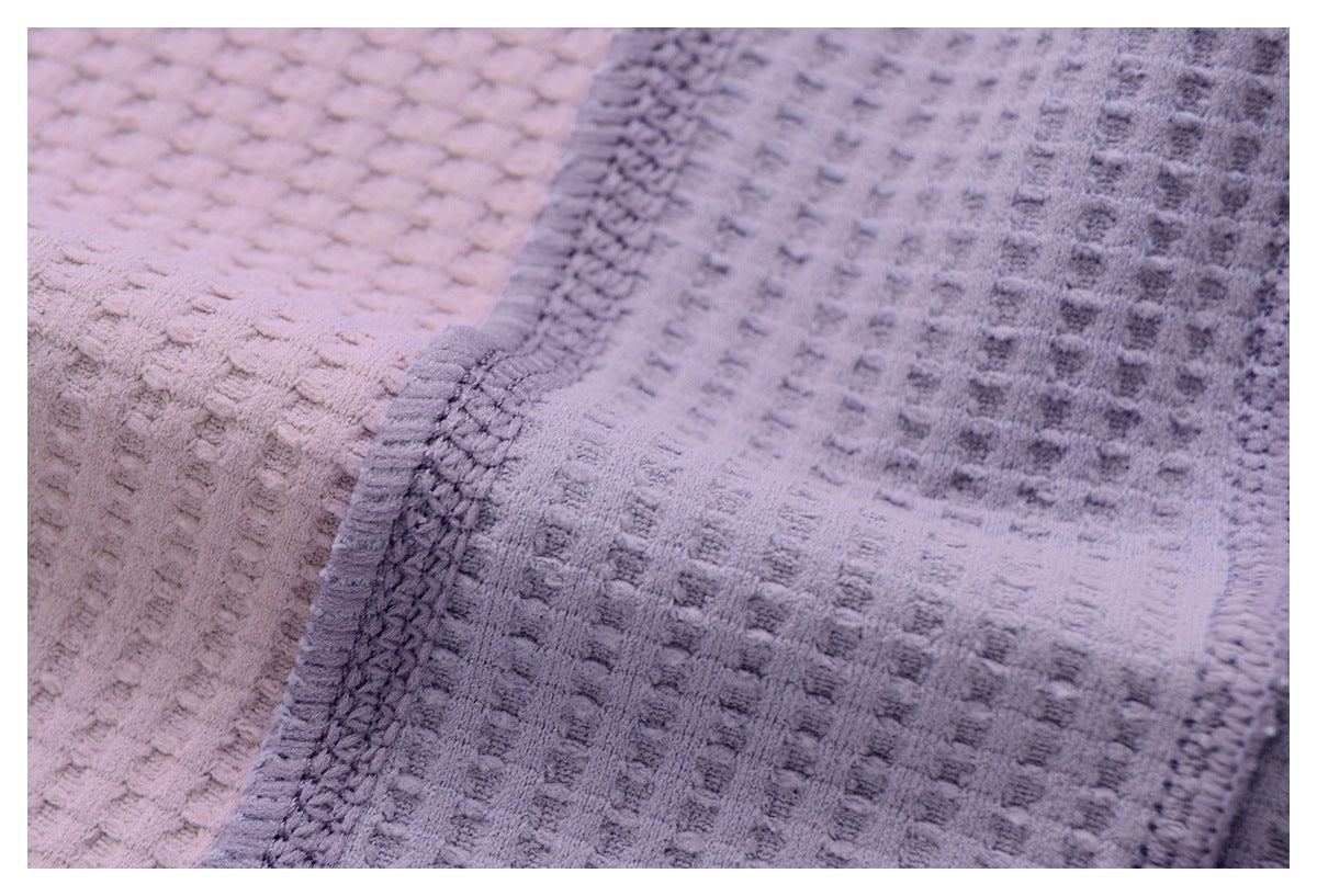 Close-up of pale pink and lavender textured fabrics with a stitched border.