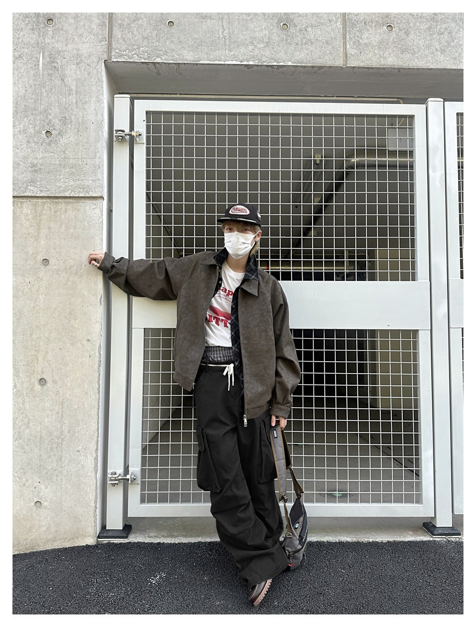 Model wearing a dark brown zip jacket, white graphic T-shirt, and loose black cargo trousers.