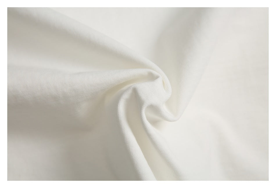 Close-up of ivory-white fabric gathered into a twist, showing its fine surface texture.