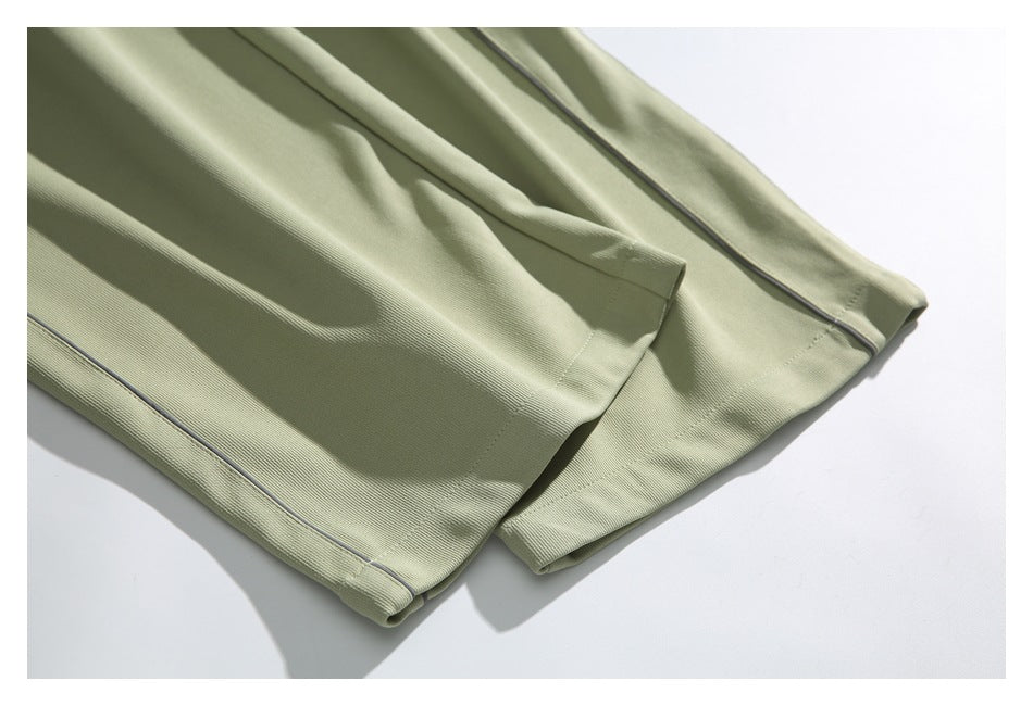 Close-up of sage green pant legs and finished hems with narrow dark piping.
