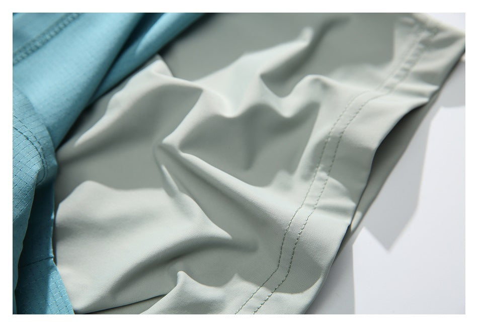 Close-up of pale gray-green fabric with a stitched edge beside turquoise fabric.